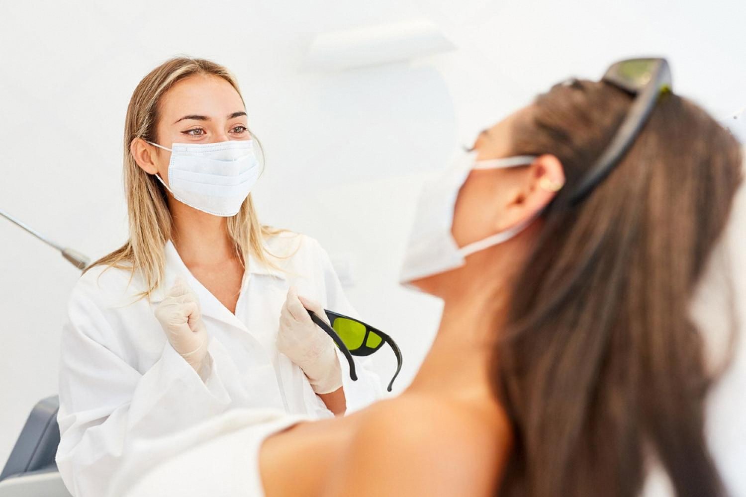 Cosmetologist holding protective goggles before a laser hair removal session in a UAE clinic